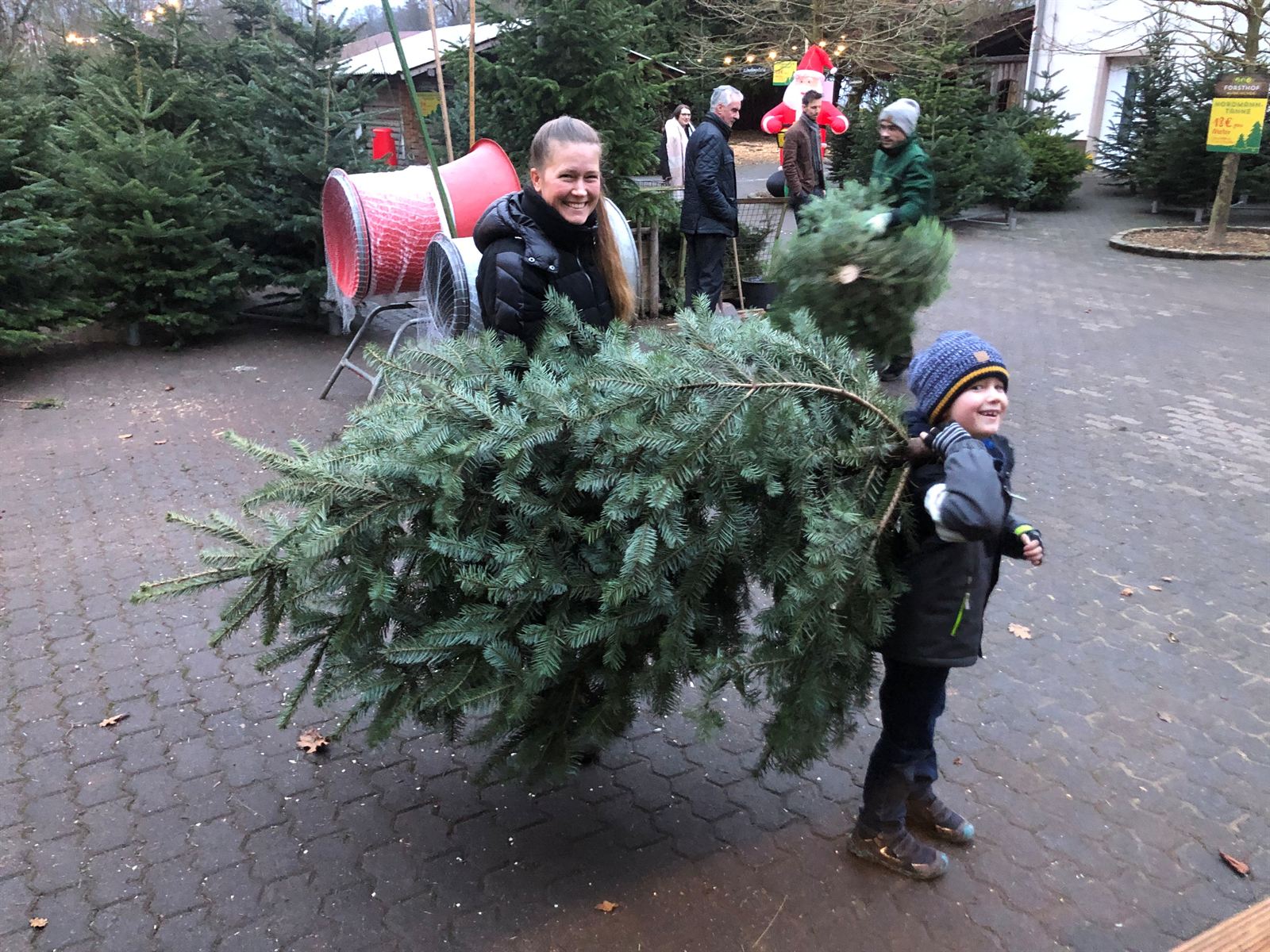 Familie mit frisch geschlagenem Weihnachtsbaum am Forsthof